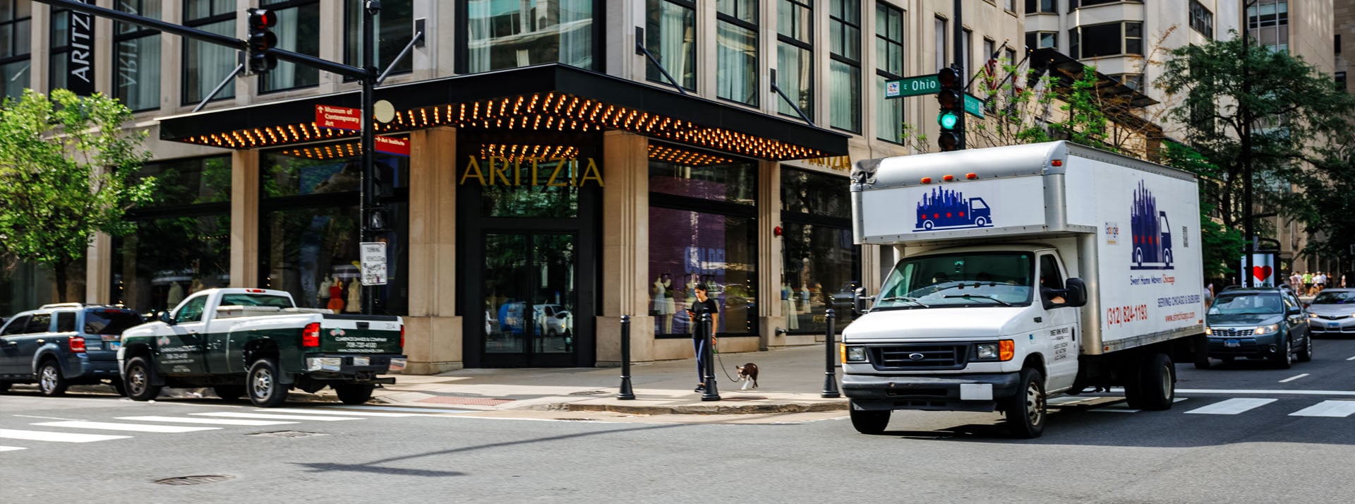 Delivery truck on city street near storefront.