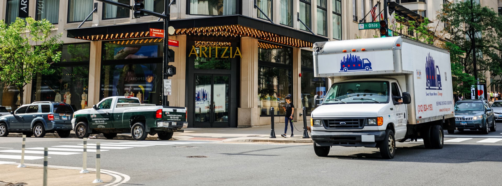 Truck passing by Aritzia store entrance on street.