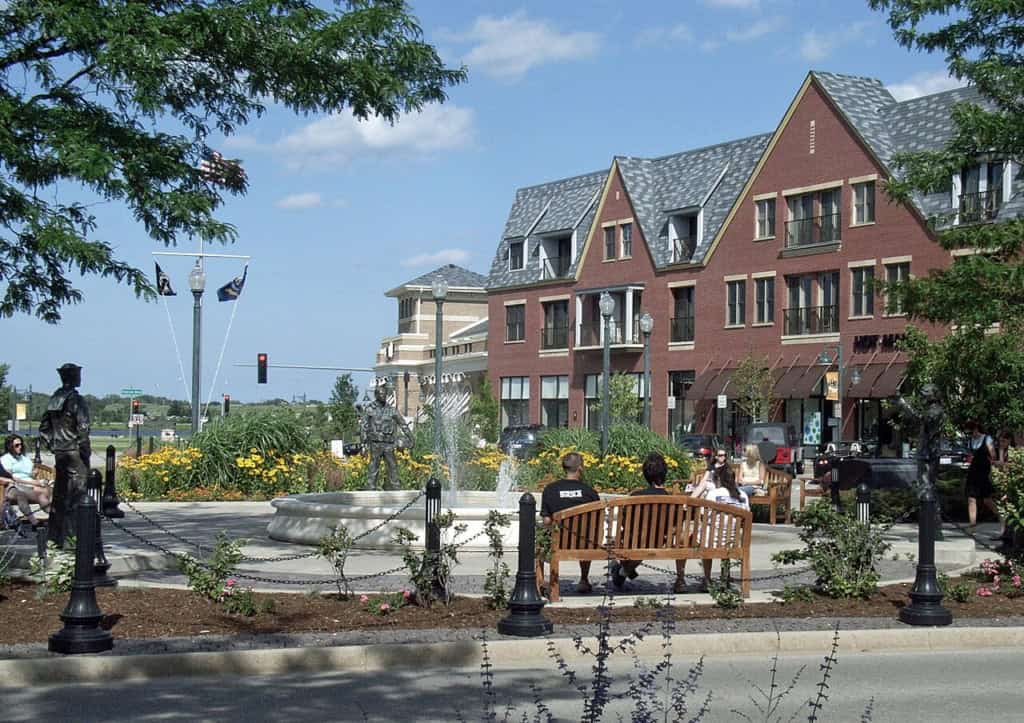 People enjoying outdoor park near brick building and fountain.